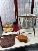 Wood folding knitting stand with quilted fabric bag and 4 assorted bags on table