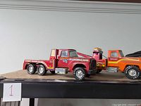 Photo showing the red six-wheeled flatbed Nylint diecast toy truck with racing decals on a shelf.