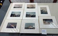 Eight signed photographs by Daniel M Finzia laid out on a table, showing maritime and coastal New England scenes, matted in white or off-white mats.