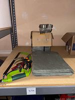 Photo showing nine pieces of slate stacked horizontally with garden tools including pruning shears visible to the left.