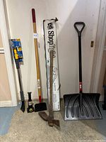 Photo showing the full lot of tools including the snow shovel, snow broom in box, scraper, pickaxe, car jack, and shop light box.