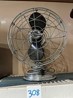 Front view of the vintage Fresh'nd-Aire metal table fan on a shelf showing protective cage and black blades