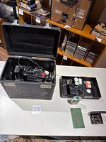 Overview of sewing machine in case with accessory tray, oil can, manual and parts