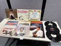 Overview of 10 vintage vinyl records laid out on a table, with 7 album covers visible and 3 loose records without sleeves to the right.
