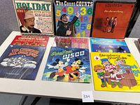 Overview photo of eight vintage vinyl records arranged on a flat surface.