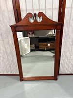Full view of vintage wooden framed wall mirror showing rectangular mirror and decorative top pediment with finial.