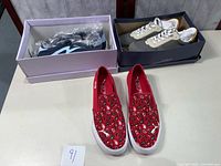 All three pairs of women's sneakers shown on a table with their boxes: red Puma slip-ons, beige Universal Thread lace-ups, black Madden Girl sneakers.