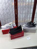 Full lot showing all three sneakers on respective brand boxes on table: Nike Air Max SC, Skechers slip-ons, Adidas Cloudfoam Pure 2.0