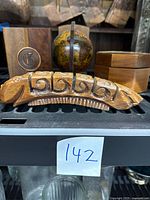 Front view of the hand-carved segmented wooden caterpillar desk accessory with two bookends and octagonal wooden box behind it.