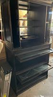 Full front view of tall black laminate wood hutch bar showing upper shelving section, mirrored back, middle drop-down surface, and lower storage including wine rack.