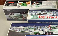 Box front showing Hess toy truck towing a gasoline tanker with airplane on top in snowy winter background.