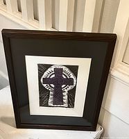 Framed etching artwork showing a purple Celtic cross on a black and white keyhole shape background.