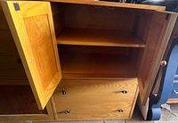 Interior shelving of cabinet behind two wooden doors inside the dresser, showing storage space