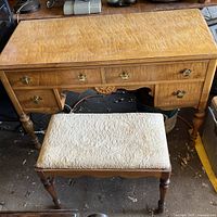 Photo showing wooden vanity table with drawers and padded seat in front