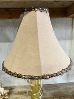 Close-up of the beige fabric lamp shade with braided trim, showing frayed edges.