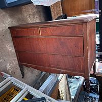 Side view of the vintage dark wood dresser showing four large drawers and two smaller top drawers with decorative carved details and visible wear.