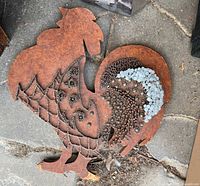 Front and angled views of a rustic metal rooster wall decor piece made with nails, staples, and tacks of various types forming decorative patterns.