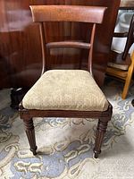 Front view of antique mahogany side chair showing curved back and upholstered seat.