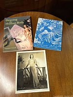 Two books and one vintage photo arranged on a wood table, showing covers and photo content