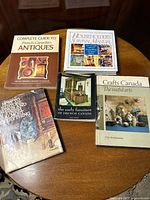 Full set of five books arranged on a wooden table, covers visible showing titles and themes on antiques and crafts.