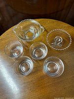 Top view of 6 pieces including four crystal bowls and two Candlewick glass bowls on wood surface.