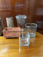 Front view of six vases and planter including pottery and glass varieties on wood surface