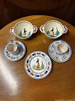 Overview of set with 2 coffee cans, 2 saucers, 2 large porringers, and 1 dessert plate all hand-painted in traditional Henriot Quimper style.