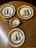 Four Henriot Quimper ceramic plates: 2 lunch plates, 1 salad plate, 1 small porringer with yellow and blue gros filet design and Breton figures
