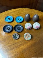 Full set of ceramic kitchen and tableware items arranged on wood surface shows candle holders, salt & pepper shakers, and butter presses in various colors and shapes.
