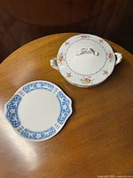 Covered casserole and cake server displayed on wooden surface, showing top view of both items.