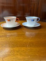 Front view of orange and blue Shelley bone china cups with matching saucers, showing hand-painted art deco squares and stripes design on each cup