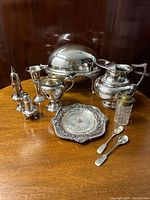 Photo showing full collection of silver plated breakfast items including warmer, jug, castor, vase, mustard pot, shakers, spoons, and butter dish.