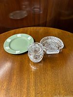 Three items shown: green Wedgwood Jasperware plate, Waterford crystal jam pot with lid, and Waterford crystal shell-shaped dish on wooden surface.