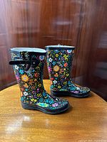 Pair of colorful floral printed tall rain boots with black background, displayed side by side showing front and side view