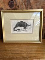Framed antique black puma print on wooden surface