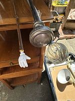 Two curtain rods and bamboo stick with a white glove pointer and back scratcher end placed on wooden furniture and nearby areas.