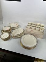 Full set displayed showing arrangement of plates, cups, pot with lid, and serving pieces on table.