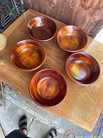 Five handmade walnut wooden bowls arranged on a wooden surface, showing shape, size, and finish.