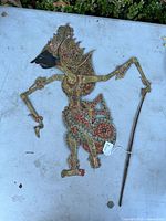 Full view of the antique Balinese shadow puppet showing its full articulated body, painted with traditional colorful patterns and signs of wear.