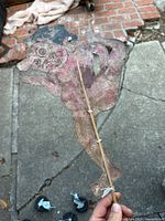 Front view of antique Balinese shadow puppet held upright showing full figure and control sticks.