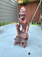 Full view of the antique carved Chinese elder statue showing the seated posture and carved base details.