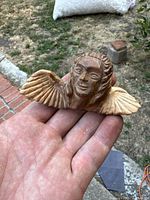 Close-up of the carved wooden angel held in hand showing face and wings.