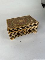Front and side view of antique rectangular jewelry box showing detailed geometric and floral inlaid design in lacquer.