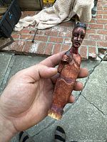 Close-up of the whole figurine from a frontal angle showing the seated figure with detailed carved face and torso.