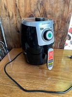 Front view of the Chefman small air fryer showing the manual dial and pull-out basket handle with safety label.