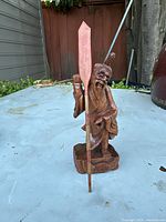 Front and side views of the vintage carved wood fisherman statue showing details of the figure, fishing pole, and base with fish motif.