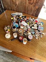 Overview photo of a large assortment of antique silk thread spools in different colors and brands, scattered on a wooden table.