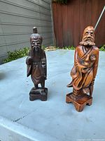 Two wooden Chinese elder and fisherman statues on a blue table outside, showing size and shape.