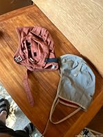 Two Soviet helmet liners on wood surface, one reddish-brown and one light gray, showing exterior and strap details.