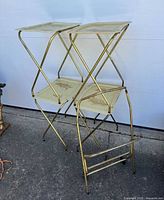 Photo showing stacked set of four fold-out fiberglass TV trays with gold-toned metal rolling cart. The trays and cart show light discoloration and dirt on surfaces.